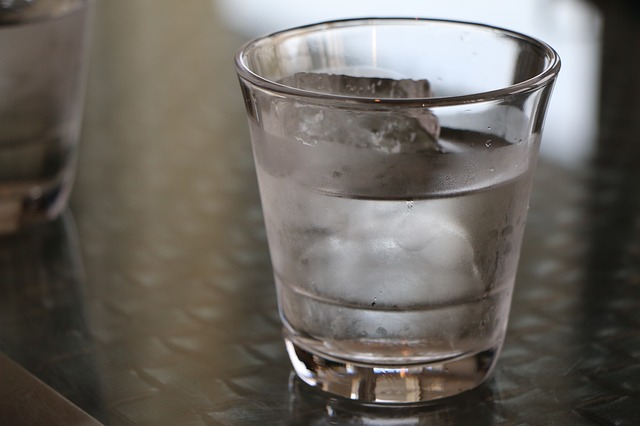 Sklenený pohár s vodou a kockami ľadu.jpg